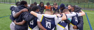 Students huddled together on an outdoor pitch at Walsall Campus, all wearing sports uniforms