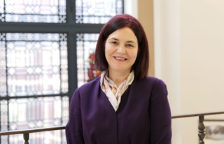 Julia Clarke, Deputy Vice-Chancellor (Student Experience), standing in front of a banister with a window behind her.